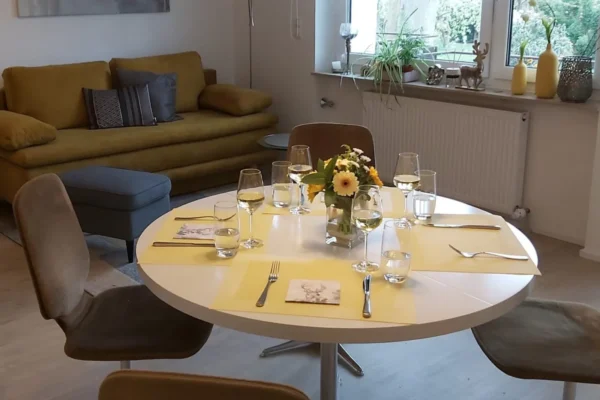Gemütlicher Essbereich der Ferienwohnung Parkblick in Deidesheim mit gedecktem Tisch und angrenzendem Wohnbereich.